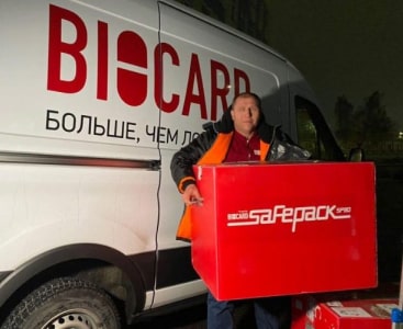 Водитель Biocard держит термоконтейнер на фоне авто. Biocard - перевозки термозависимых грузов с температурным режимом по РФ 